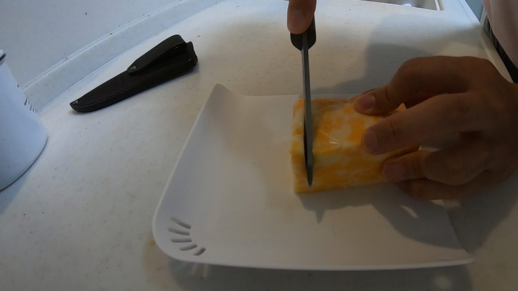 ナイフでチーズの塊を切る